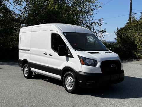 A white 2021 Ford Transit van with a black front grill and silver hubcaps parked on a flat surface