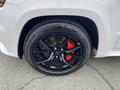 A close-up of a black alloy wheel with a silver brake caliper on a 2018 Jeep Grand Cherokee showcasing the tire tread pattern