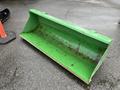A green metal front loader bucket designed for a 2003 John Deere 790 tractor showing wear and rust on the interior surface