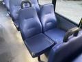 A row of blue fabric bus seats with rounded backs and armrests showing signs of wear and tear