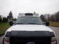 A 2009 Ford F-450 Super Duty truck with visible front grille and hood graphics topped with a spare tire and orange lights on the roof