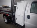 A white 2008 Ford F-550 with a flatbed and a utility box attached to the side of the truck near the rear wheel