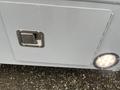 A close-up of a silver panel with a metal latch and a circular light on a 2017 Chevrolet Express van