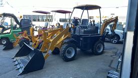 A 2024 AGT BH50G utility vehicle with a yellow front loader and backhoe attachment positioned in a workspace among other machinery