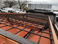 A close-up view of a 2009 Ford F-550 truck bed with a grid metal cover showing an orange surface underneath