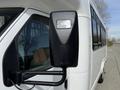 A black side mirror of a 2010 Ford Econoline van reflecting part of the vehicle's white exterior and nearby trees