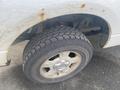 A close-up of a 2009 Ford F-150 tire showing worn tread and rust on the wheel rim