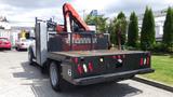 A 2014 RAM 5500 truck with a flatbed and attached crane on the rear side featuring a metal railing and multiple red and white lights along the back edges