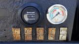 Close-up of control panel featuring a Honeywell hour meter and several weathered switches with faded labels for various functions and a gauge displaying pressure and load levels