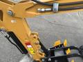 Close-up of a yellow 2024 AGT Mini Excavator's arm and hydraulic components showing warning labels and a bucket attachment