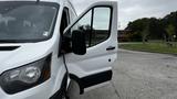 A white 2017 Ford Transit van with the driver's door open showing the interior dashboard and seat