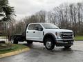 A 2022 Ford F-550 pickup truck with a white exterior and flatbed design parked on a driveway