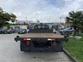 A 2012 Ford F-550 truck viewed from the rear with a wooden flatbed and a black frame