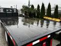 A 2011 International DuraStar 4300 flatbed truck with a shiny wet surface and a black metal frame