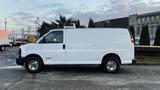 A white 2005 Chevrolet Express van parked on a paved area showcasing its side profile and chrome wheels