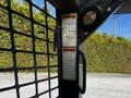 A close-up view of warning labels and controls on a Gehl R105 compact loader's interior panel