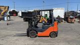 A 2018 Toyota 8FGCU25 forklift with a black and orange body is positioned sideways showing its forks and cab