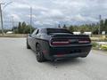 A black 2017 Dodge Challenger parked on a gravel road with a sleek rear design and dual exhausts