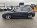 A 2014 Subaru Impreza hatchback in dark gray with five doors and alloy wheels parked on a wet surface