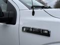 A close-up of a 2018 Ford F-150 XLT badge on the side of a white truck with droplets of water on the surface