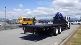 A 2017 Freightliner M2 106 flatbed truck with a crane attached in the back parked in a lot