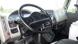 The interior of a 2008 International 7500 featuring a black steering wheel dashboard controls and gear shift with various instruments and buttons