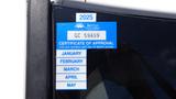 A sticker on a vehicle window showing a 2025 certificate of approval with a blue background and month labels for January to May.