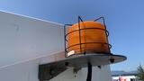 An orange warning light mounted on a metal base attached to a vehicle