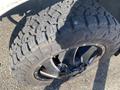 Close-up of a rugged tire mounted on a black wheel belonging to a 2000 Ford F-350 SD showcasing an aggressive tread pattern