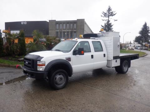 A 2009 Ford F-450 SD with a white exterior and a flatbed equipped with a storage box on the back