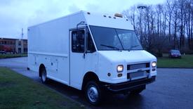 A 2000 Freightliner Utilimaster box truck with a white exterior and large front windows parked on a paved surface