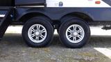 A close-up view of two silver alloy trailer wheels featuring black tires attached to a 2021 Forest River 312BH East To West Della Terra