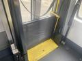 A folded wheelchair ramp with a yellow surface and a mesh barrier attached to a Chevrolet Express interior