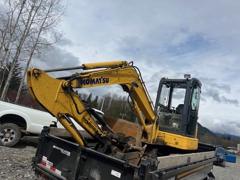 A yellow 2006 Komatsu PC55MR2 excavator with a cab and large digging arm is mounted on a flatbed truck
