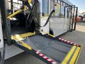 A 2018 Chevrolet Express with a deployed wheelchair ramp featuring a textured surface and yellow safety grips