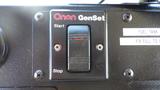 A black control panel with a red Onan GenSet label featuring a start and stop switch with a small orange indicator light