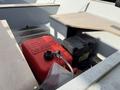 A red fuel tank sits on the floor of a boat next to a black battery box and a flat surface where gear can be placed