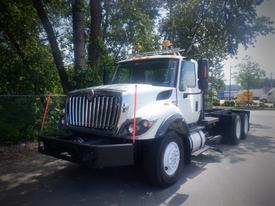 A 2012 International 7400 truck with a white cab and large front grille is parked on the road with safety lights mounted on top