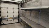 A 2006 Ford Econoline van with an empty interior featuring metal shelves along the sides and a closed rear door