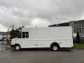 A 2011 Ford Econoline truck with a white exterior and boxy design parked with its side view visible