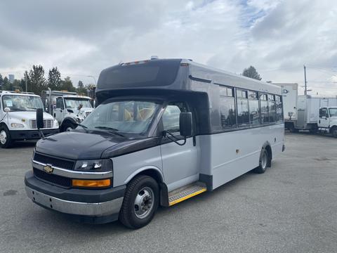 A 2017 Chevrolet Express bus with a black front, large side windows, and a step at the entrance