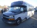 A 2016 Chevrolet Express bus with a black front and white body featuring large windows and a low step entry