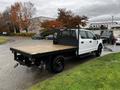 White 2020 Ford F-350 SD flatbed truck with a black mesh cab protector and wooden flatbed positioned at an angle