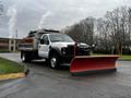 A 2009 Ford F-550 truck equipped with a red snow plow attached to the front