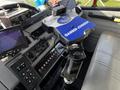 The interior view of a 1994 Freightliner FL80 featuring a control panel with various buttons a Gamber-Johnson mount and a screen displaying camera feed
