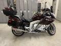 A 2013 BMW K1600GTL motorcycle in dark brown color with a large rear storage compartment and a sleek design showcasing its touring capabilities