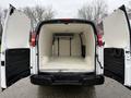 A 2009 Chevrolet Express van with open rear doors revealing an empty interior with a flat loading floor and padded walls