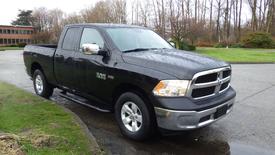 Black 2017 RAM 1500 pickup truck parked with a cab and bed, featuring chrome accents and four doors