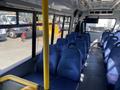 Interior view of a 2017 Chevrolet Express with blue seats and yellow poles; rows of seating are visible along the sides of the vehicle