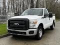 A 2011 Ford F-250 SD in white with a black grille and front bumper parked with the driver's side door open